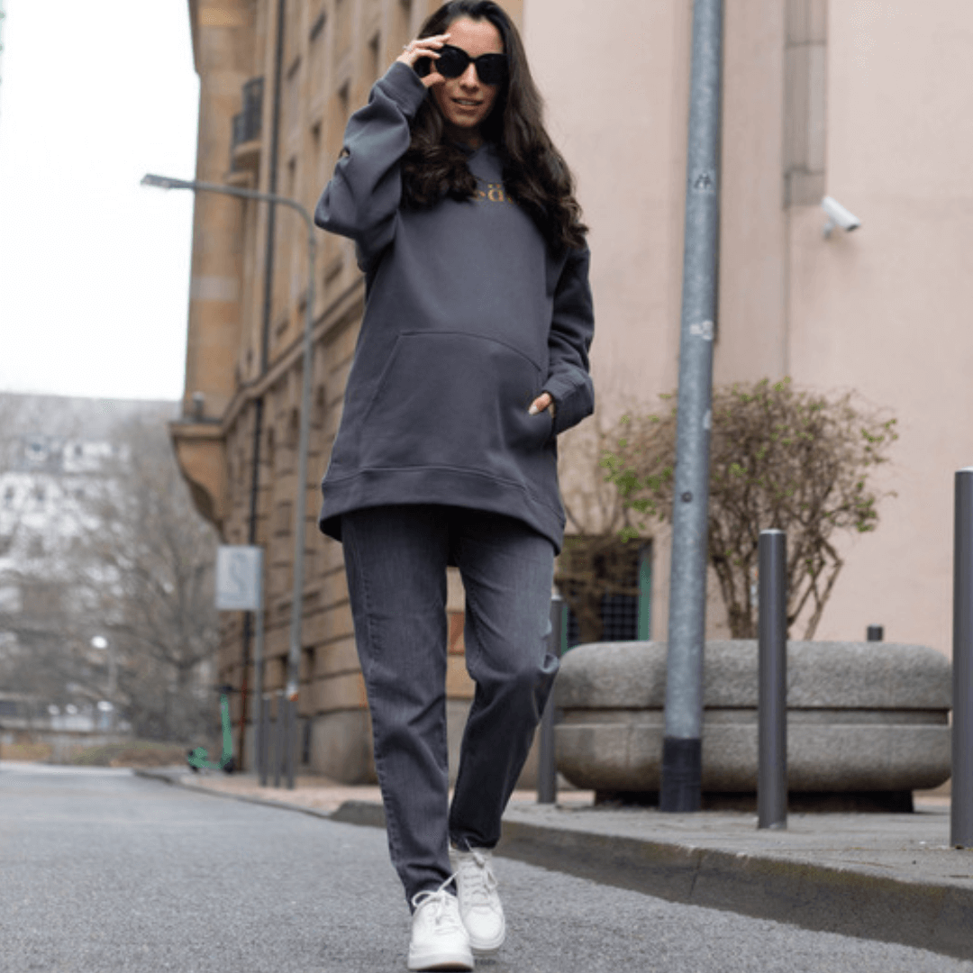 Schwangere Frau im creätr Outfit mit grauem Hoodie und Umstandsjeans