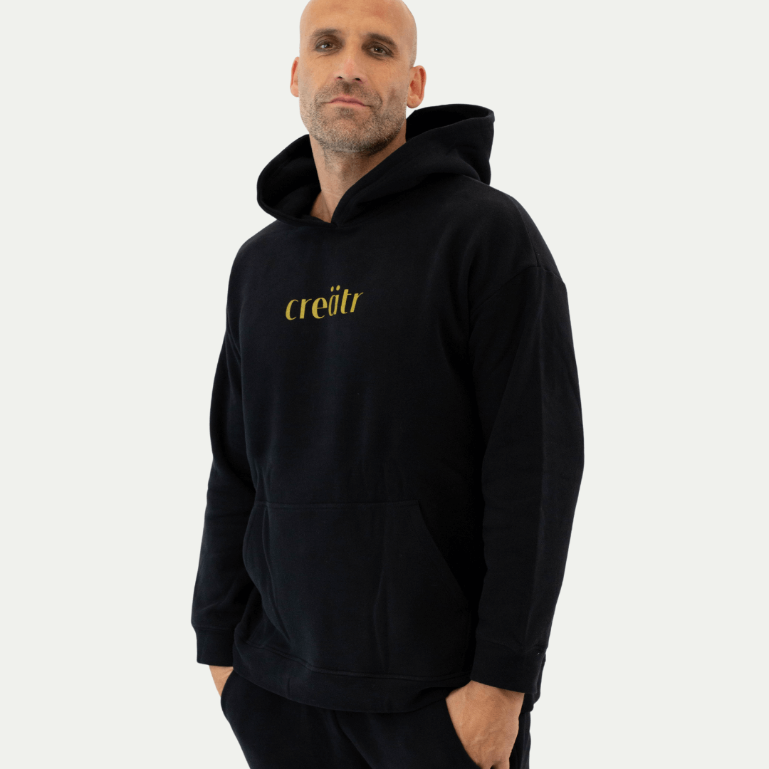 Mann im schwarzen creätr Hoodie mit goldenem Logo