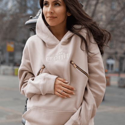 Schwangere Frau im rosa-beige Hoodie mit creätr Logo und Reisverschluss