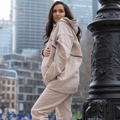 Schwangere Frau im rosa-beige Hoodie mit creätr Logo und Reisverschluss, und Jogger